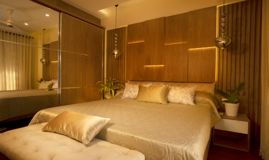 Luxurious bedroom design with gold-accented paneling, ambient lighting, and mirrored sliding wardrobe doors in India